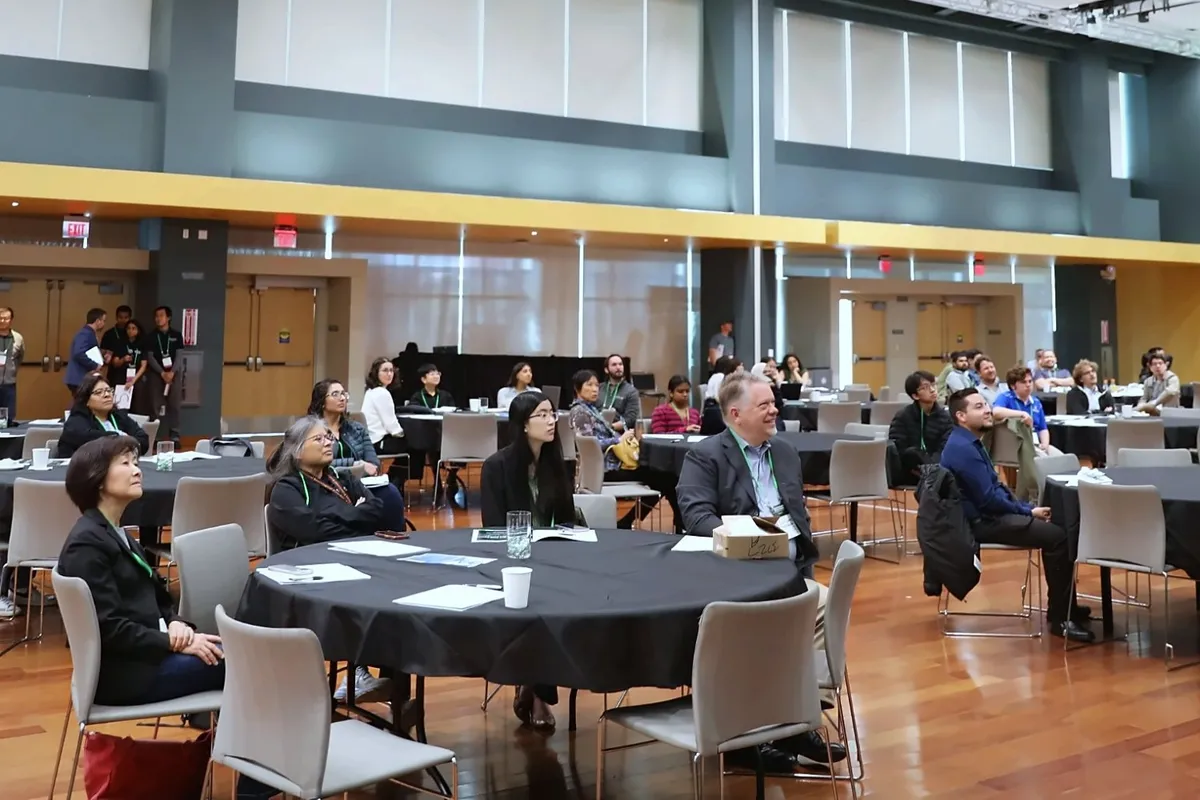 Attendees seated at round tables in a ballroom, watching a presentation at a past BABDC conference.
